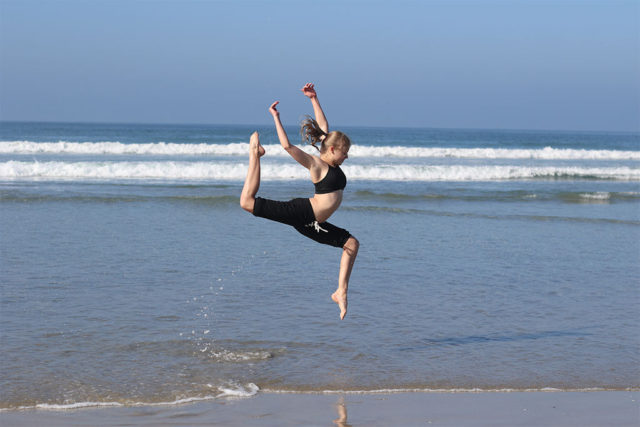 female dancer joyfully leaping on the beach