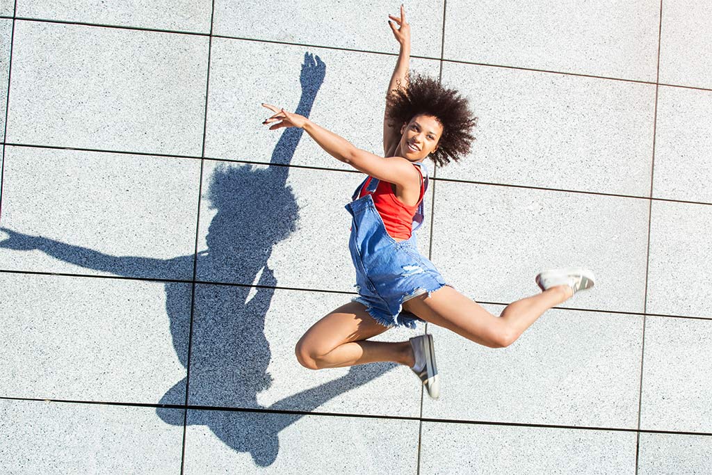 smiling dancer jumping next to wall