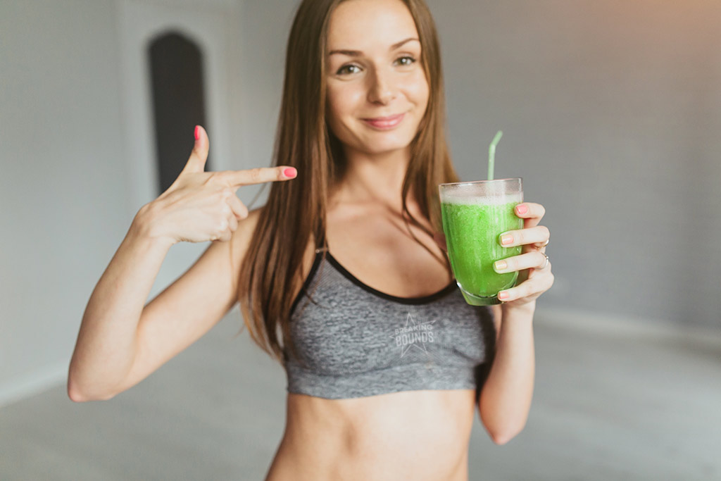 Girl in workout clothes enjoying a green smoothie