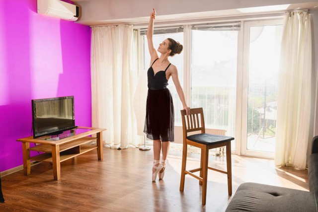 Women ballet training at home with a chair.